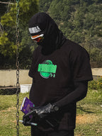 Person wearing a black hoodie and gloves, holding a book, with a forest background.